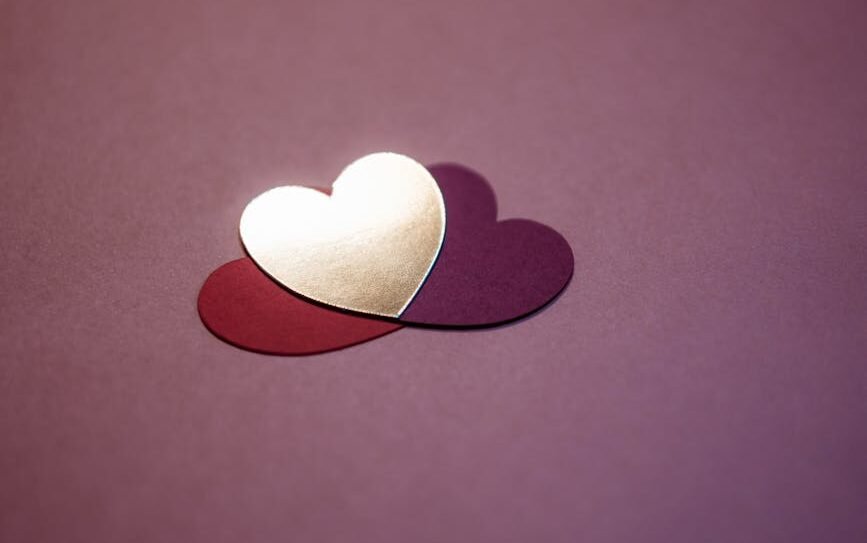 Two overlapping heart shapes on a purple background symbolize love and affection.